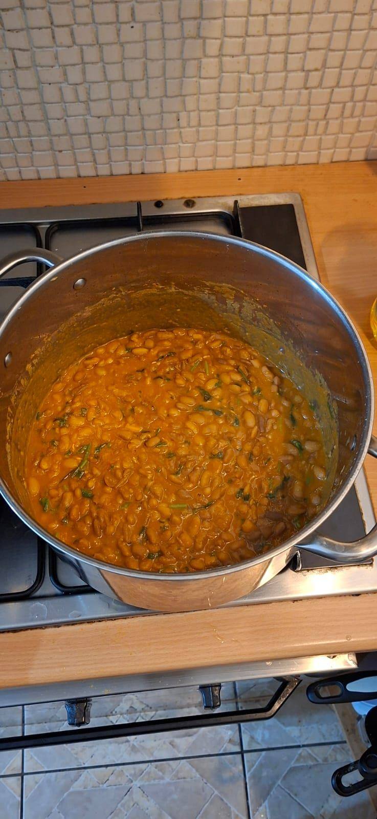 A tray of Kenyan beans in coconut milk set out on a shared potluck table