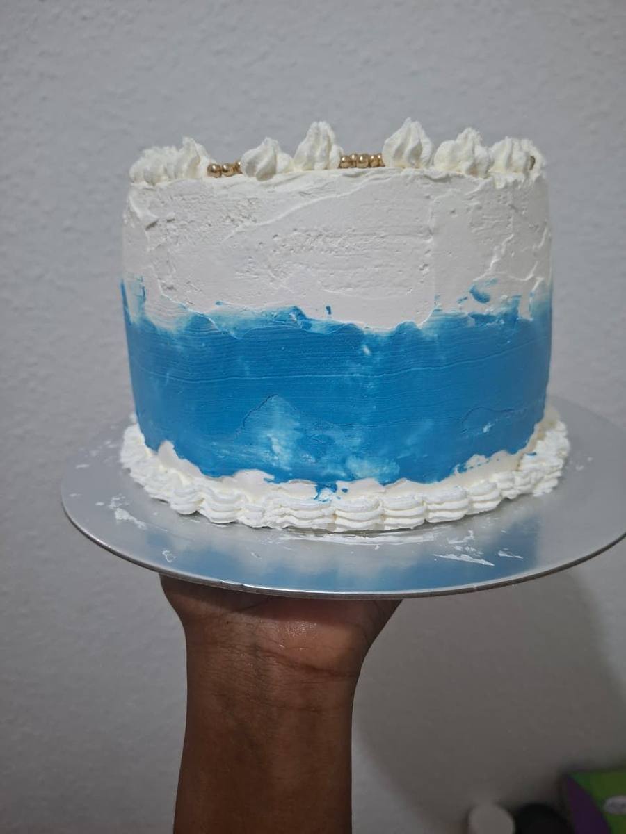 Tall cake finished in blue-to-white buttercream with piped shells and gold pearls