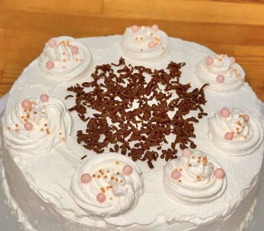 Cream cake topped with chocolate shavings, rosettes and pink pearls